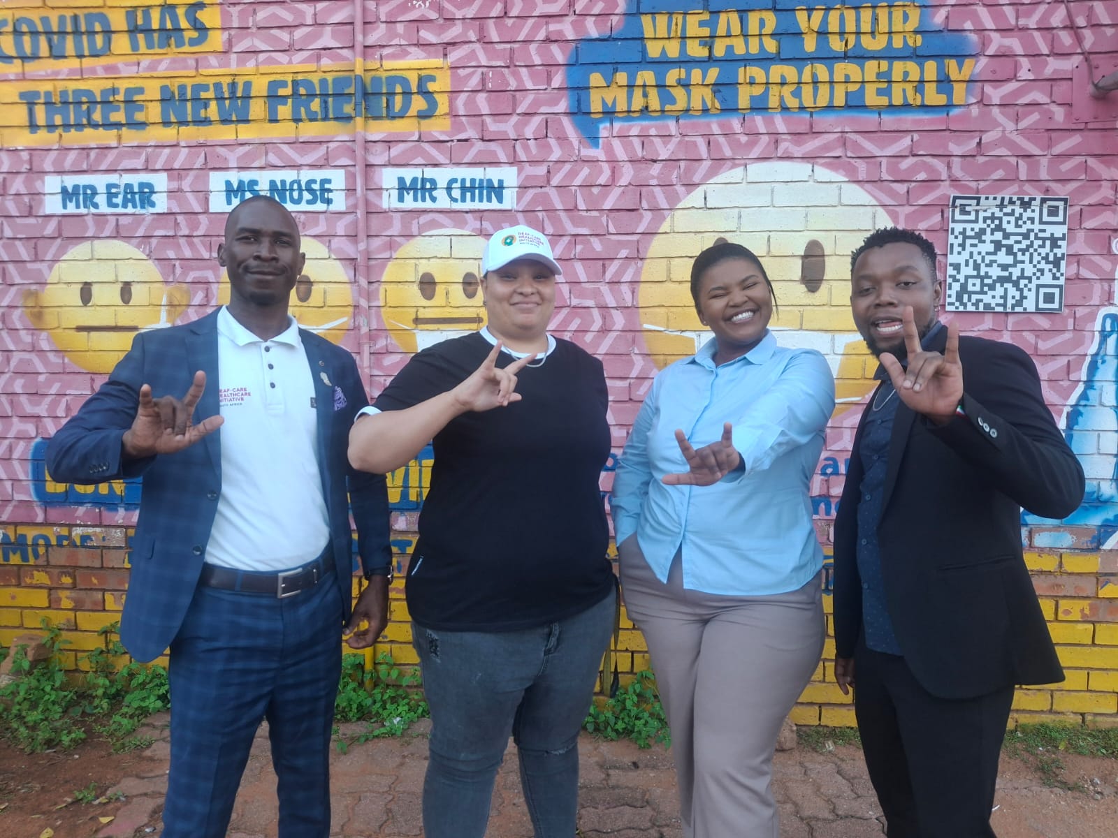 DCHI team in front of a COVID-19 wear-your-mask-properly mural